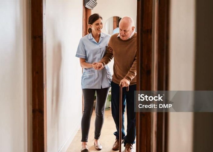 Shot of a young nurse assisting a senior man with a walking stick in a retirement home
